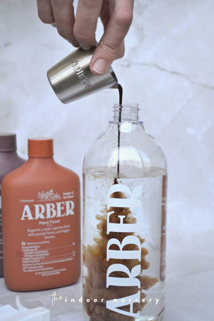 pouring arber plant food into water bottle